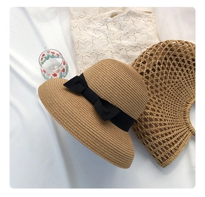 Detail shot of woven straw hat featuring a black ribbon bow and natural beach accessories