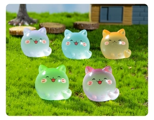Group of five translucent luminous cat figurines in various gradient colors on green grass