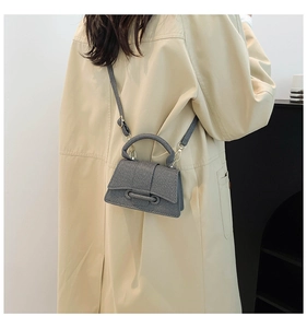 Détail du petit sac gris texturé avec nœud décoratif et bandoulière réglable