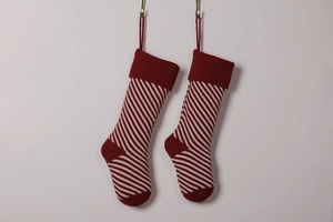 Pair of red and white striped knit Christmas stockings hanging on hooks against white wall