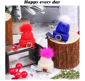 Detailed view of mini knitted Christmas hat clips with fur balls and rhinestone accents