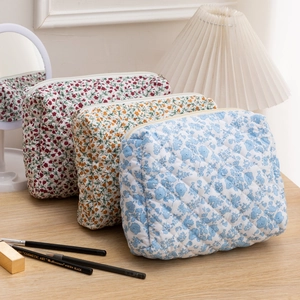 Close-up of quilted floral cosmetic bags in red, yellow, and blue colors with zipper