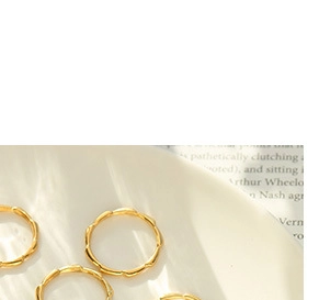 Macro detail of gold bamboo texture rings on a ceramic tray with soft natural lighting