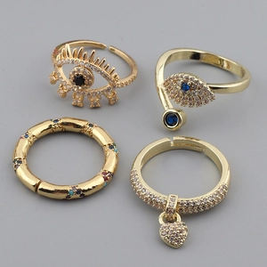 Four-piece gold evil eye ring set with blue crystals and heart pendant charms