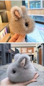 Detailed plush rabbit charms in brown and grey faux fur shown in a hand-held close-up