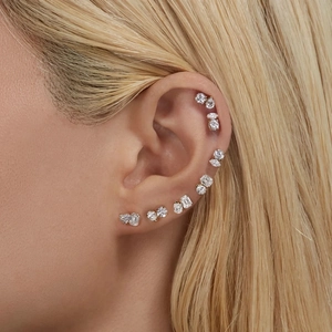 Macro shot of assorted geometric zircon stud earrings worn on the earlobe and cartilage