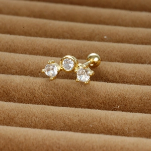 Détail d'un clou d'oreille doré avec trois zircons et fermoir à vis sur velours