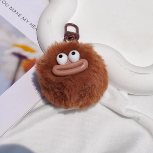 Close-up of brown plush ball keychain with quirky big eyes and thick lips detail