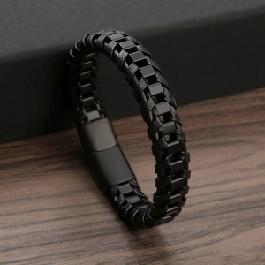Vintage braided black leather and matte black steel bracelet on wood background