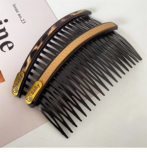 Detail of two hair side combs with leopard print, brown leather and gold bear motifs
