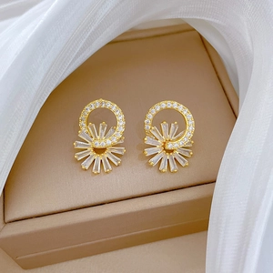 Detailed shot of gold flower earrings with micro-inlaid zircons on a luxury jewelry box
