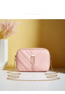 Detailed view of pink crossbody bag with V-shaped quilting and gold metal buckle