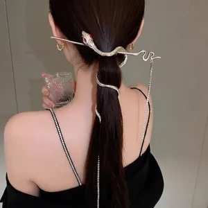 Silver snake hair pin with tassel and red stone eyes worn in a ponytail bun