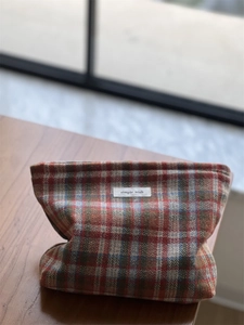 Detail of vintage red and green plaid tweed makeup bag with a minimalist woven label