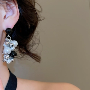 Close-up of beaded tassel earrings with pearls and black crystals on model
