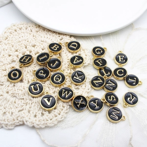 Detailed close-up of double-sided black enamel letter charms with gold alloy edges