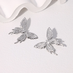 Macro shot of silver butterfly stud earrings with detailed metallic wing textures