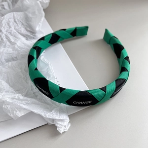Detail of woven fabric headband in green and black with white CHANGE lettering