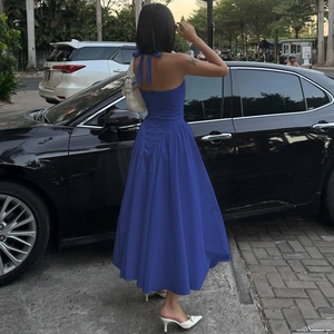 Rückansicht eines blauen rückenfreien Neckholder-Kleides mit schwingendem Rock im Freien