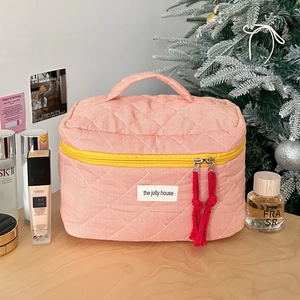 Detail of pink quilted makeup bag featuring yellow zipper and unique red knot puller
