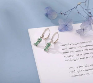 Macro detail of S925 sterling silver dinosaur earrings with green zircon stones