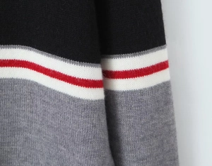 Vue détaillée du pull en tricot rayé montrant la texture bicolore et les fils tissés