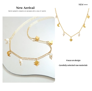 Detail of gold star and moon tassel necklace with natural freshwater pearls and metal charms