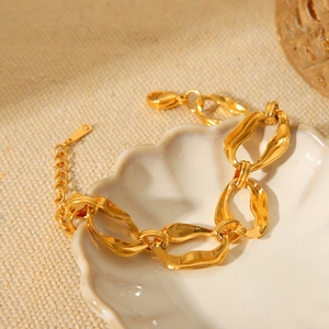 Irregular 18K gold stainless steel chain bracelet displayed on a white shell plate