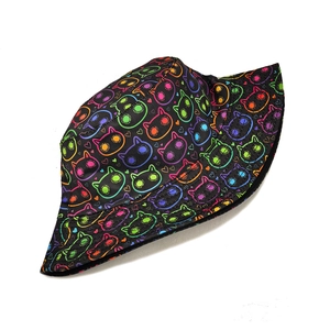 Close-up of neon cat face and heart patterns on a black canvas bucket hat fabric