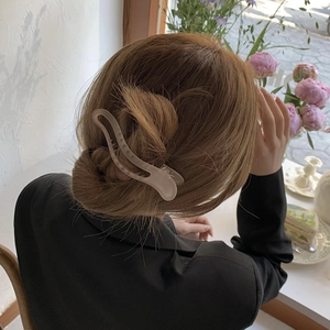 Detail of a beige matte shark hair claw clip styled on a woman's bun hairstyle
