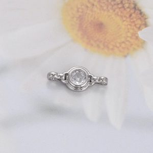 Macro view of a silver-toned metal charm with round clear zircon and dual connectors