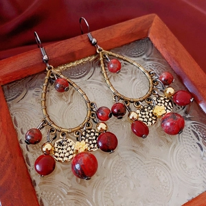 Détail de boucles d'oreilles vintage en forme de larme avec pierres rouges et franges