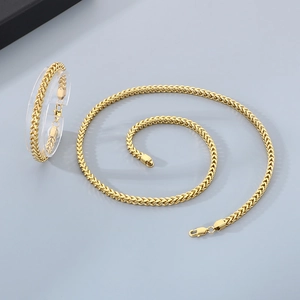 Detail of golden wheat chain necklace and bracelet set with polished metal texture