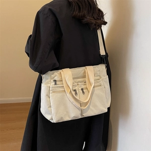 Minimalist corduroy shoulder bag in off-white with adjustable straps and front pockets