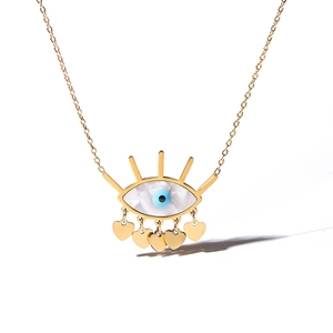 Macro detail of gold devil's eye necklace pendant featuring blue iris and heart charms