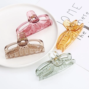 Set of 4 transparent hair claw clips in pink, amber, and green tones on a tray