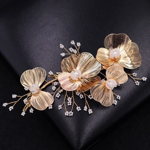 Elegant gold flower bridal headpiece with white pearls and woven metal petals on dark leather