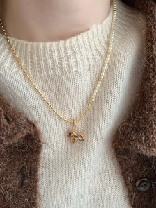 Detail of horse pendant necklace featuring gold plating, pearls, and colorful gemstones