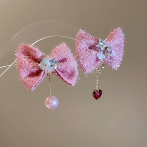 Detail of pink bow earrings featuring sparkling fabric with pearl and red heart pendants
