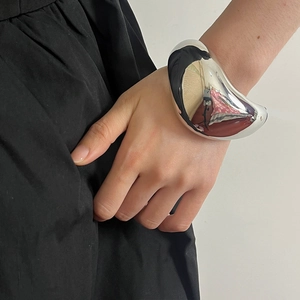 Detailaufnahme eines glänzend silbernen geometrischen Armreifs am Handgelenk