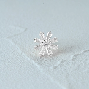 Macro shot of silver flower stud earring featuring round and rectangular clear gemstones