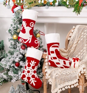Close-up of red Christmas stockings with reindeer and snowflake embroidery hanging by a fireplace