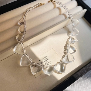 Close-up of clear heart-shaped acrylic beads with golden metal clasp in a jewelry box