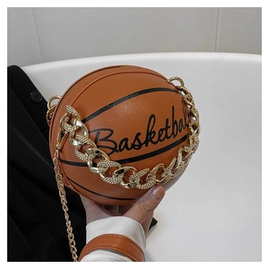 Detail of orange basketball-shaped bag featuring a chunky gold chain strap and cursive text