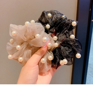 Detailed close-up of champagne and black organza scrunchies with white pearls
