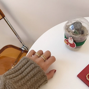 Detail of gold hollow mesh ring with sparkling zircon stones worn on hand in a cafe