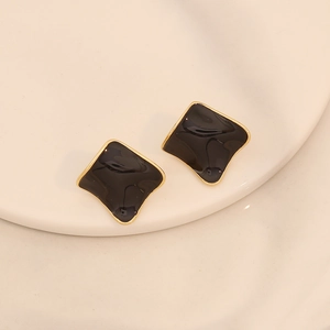 Gros plan de boucles d'oreilles géométriques en émail noir et bordure dorée