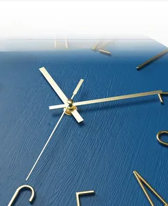 Detail of elegant gold metal hands and 3D hour markers on blue textured wall clock
