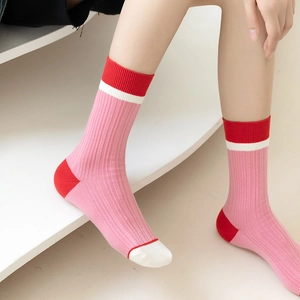 Close-up of pink crew socks with red contrast heel and white toe in ribbed cotton knit