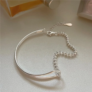 Macro shot of S925 sterling silver beaded bracelet featuring heart charm on stone surface